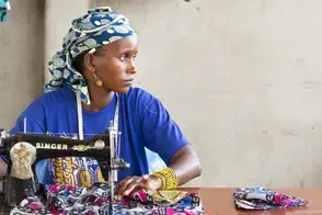 A seamstress sits at her sewing table