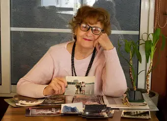 Flutura Xhabija, at 76, pictured with photo prints of her participation in Beijing in 1995. Photo: UN Women/Yllka Parllaku