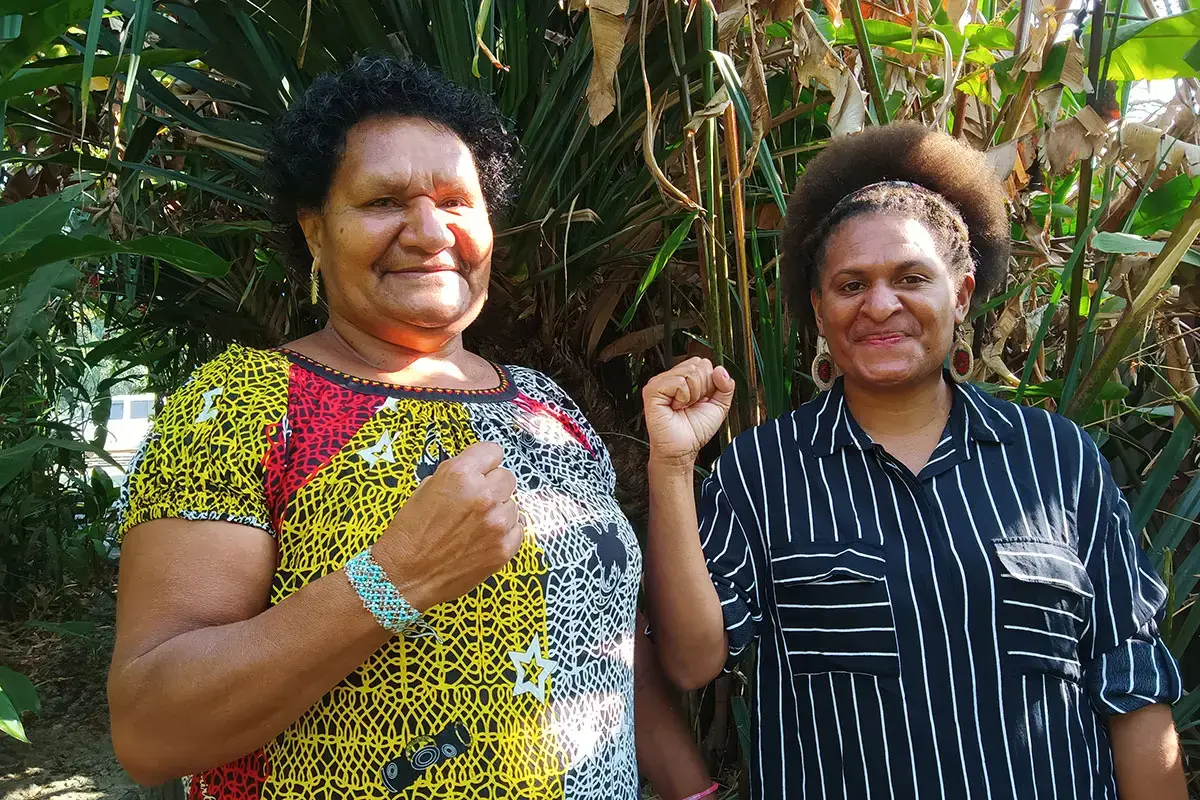 Two women from Papua New Guinea raise their fists